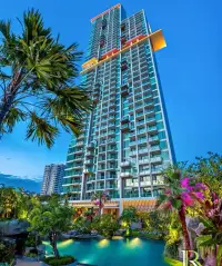 2 Bedroom Condo for Sale at Riviera Wong Amat Beach twilight view of high-rise tower with tropical garden and pool
