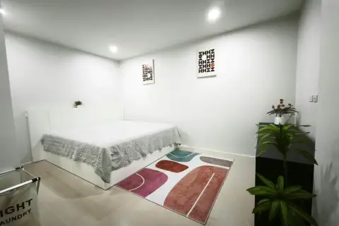 2 Bedroom Condo for Rent at Royal Hill Resort bedroom with white bed, geometric wall art, and colorful rug