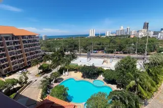 Royal Hill Resort main entrance and large outdoor swimming pool with sun loungers, surrounded by tropical plants.
