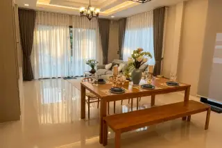 SP Village 1 open-plan dining and living room with wooden table, bench seating, chandelier, and marble tile floors