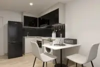Studio Condo for Sale at The Indeed Condo Pattaya compact kitchen with black cabinetry, Samsung fridge, and dining table for two