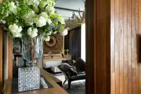 1 Bedroom Condo for Sale at Cetus Beachfront bedroom viewed through doorway with floral arrangement, antler chandelier, and driftwood wall clock
