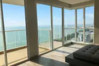3 Bedroom Condo for Sale at Cetus Beachfront bright living room with wraparound glass windows and direct beachfront ocean view