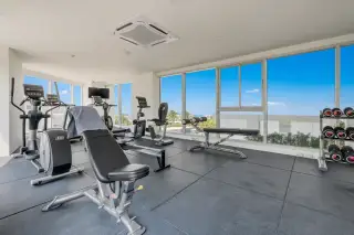 Sands Condominium modern fitness center with various exercise machines, weights, and large windows.