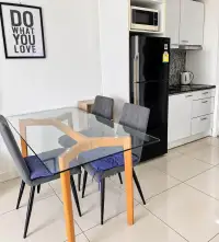 2 Bedroom Condo for Rent at Siam Oriental Plaza dining table with kitchen, fridge, and microwave in background