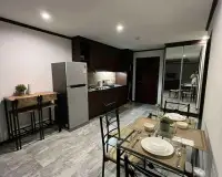 2 Bedroom Condo for Rent at Siam Oriental Twins open kitchen with wooden cabinets, fridge, and glass dining table