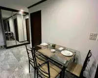 2 Bedroom Condo for Rent at Siam Oriental Twins dining area with glass table, place settings, and mirrored closet