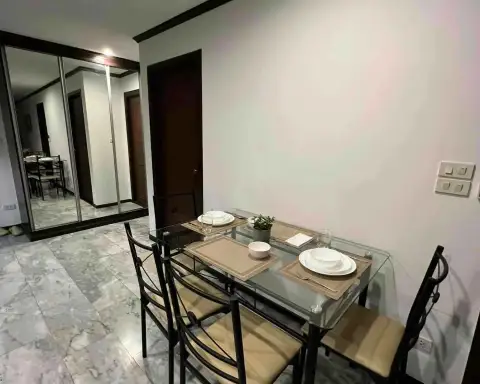 2 Bedroom Condo for Rent at Siam Oriental Twins dining area with glass table, place settings, and mirrored closet