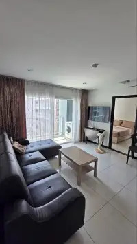 1 Bedroom Condo for Sale at Siam Oriental Tropical Garden living room with leather sofas, TV and balcony view