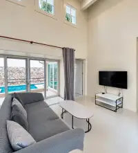 3 Bedroom House for Sale at Silk Road Place high-ceiling living area with sofa, TV stand and poolside sliding doors