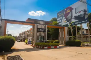 Sirinda Primo entrance gate with a large billboard, inflatable tube man, and road leading to townhouses.