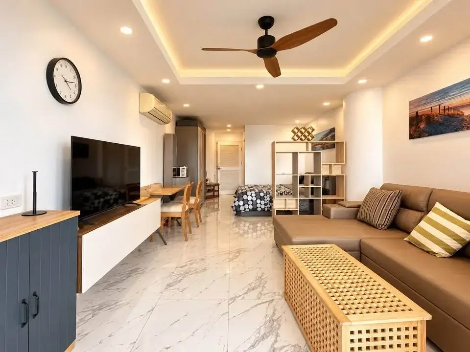 Studio Condo for Rent at Sky Beach open-plan living area with leather sofa, TV, dining table, and bedroom nook