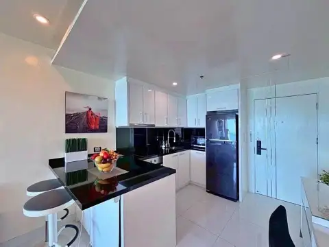 1 Bedroom Condo for Sale at Sky Residences Pattaya modern kitchen with black countertops and fridge