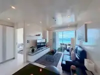 1 Bedroom Condo for Sale at Sky Residences Pattaya living room with leather sofa and sea view balcony