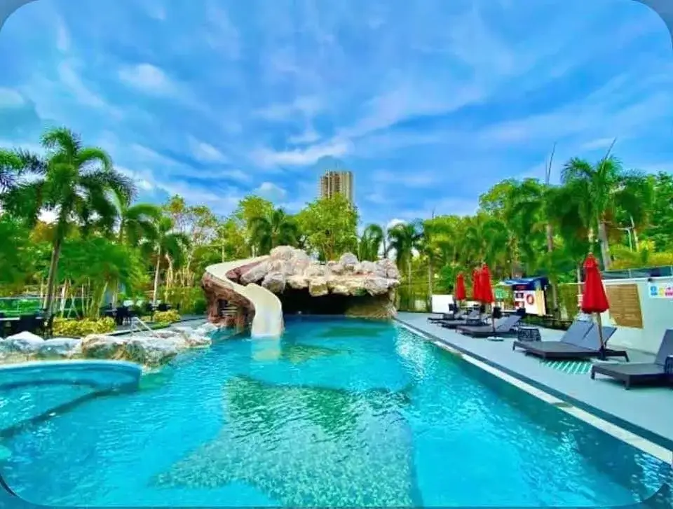 1 Bedroom Condo for Sale at Sky Residences Pattaya outdoor pool with rock waterslide and palm trees