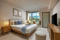 Studio Condo for Sale at SKYPARK Lucean Jomtien Pattaya bed with grey linens facing floor-to-ceiling windows overlooking coastline