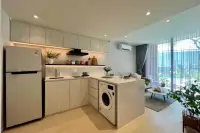 1 Bedroom Condo for Sale at Celine Wongamat: Kitchen with integrated washing machine, refrigerator, and living area in background.