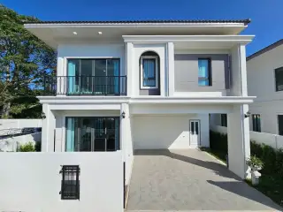 Spring Town Pool Villa Pattaya two-story house with a white facade, black balconies, and a covered parking area.
