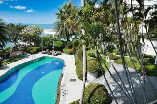 Sugar Beach balcony view of the swimming pool, tropical garden, and distant ocean.