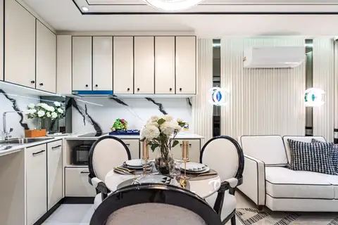 2 Bedroom Condo for Sale at Embassy Life, dining table with floral centerpiece, kitchen, and white sofa in living area.