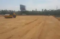 Land for Sale in Nong Pla Lai, wide view of a cleared dirt plot with a road roller and a person, trees, and highway.
