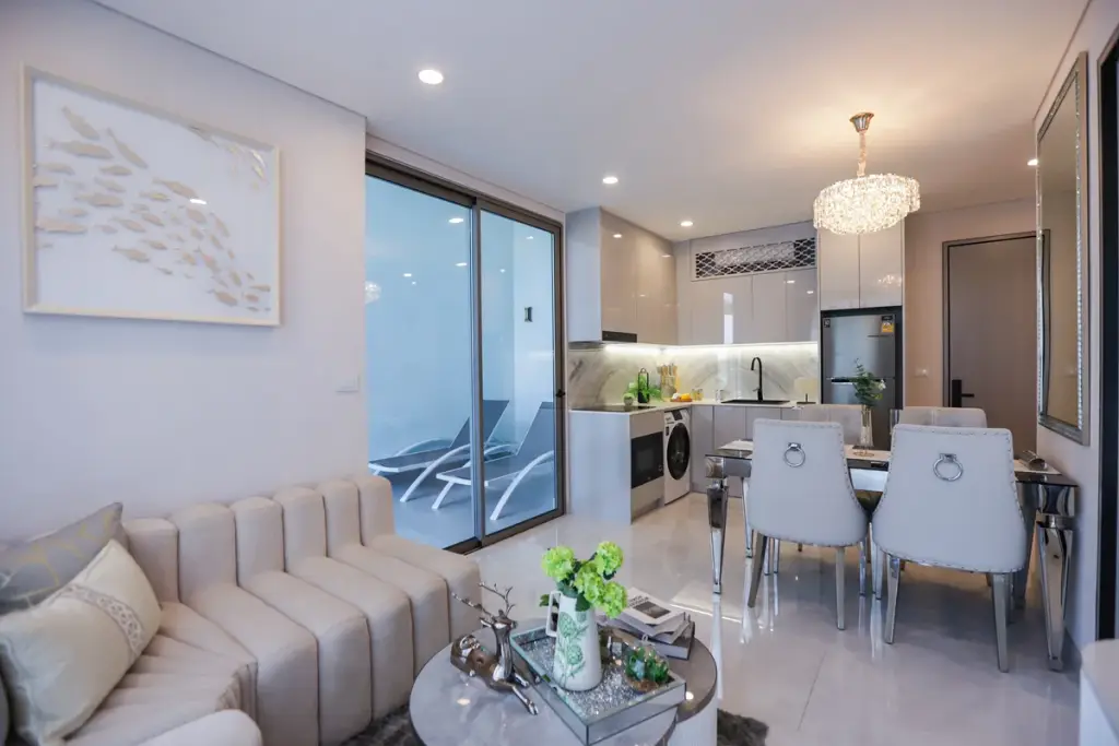 1 Bedroom Condo for Sale at Copacabana Coral Reef open-plan living room with cream sofa, dining area, modern kitchen and private pool access