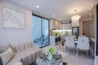 1 Bedroom Condo for Sale at Copacabana Coral Reef open-plan living room with cream sofa, dining area, modern kitchen and private pool access