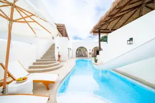 The Sunshine House poolside area with water slide sun loungers large parasol and arched entrance facade