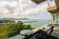 1 Bedroom Condo for Sale at Del Mare spacious balcony with lounge chairs, glass table, and sweeping ocean and hillside views