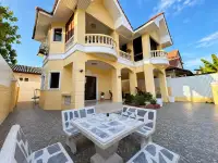 3 Bedroom House for Sale & Rent in East Pattaya two-story yellow villa exterior with curved balconies and stone patio seating
