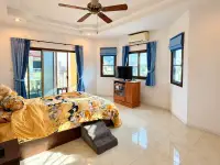 3 Bedroom House for Sale & Rent in East Pattaya master bedroom with yellow bedding, balcony access and wall-mounted TV