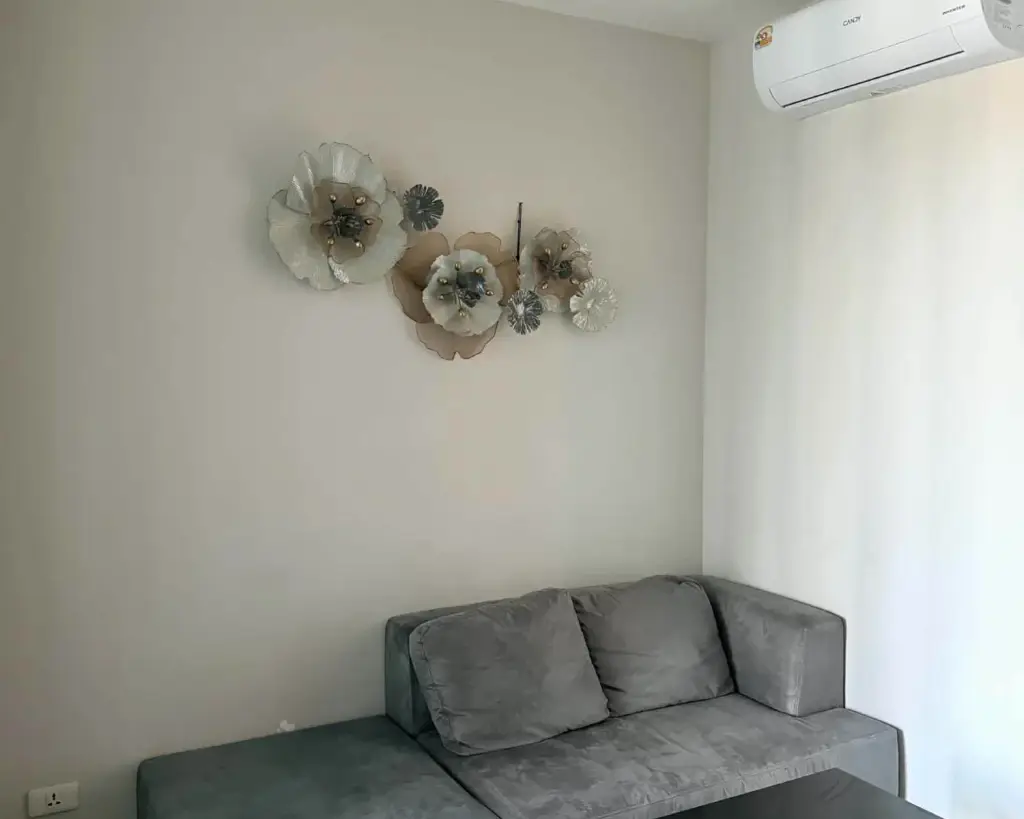 1 Bedroom Condo for Rent at The Base Central Pattaya gray sofa with decorative wall flower art and air conditioner