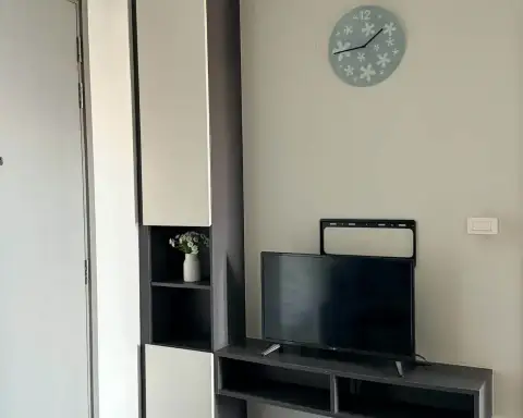 1 Bedroom Condo for Rent at The Base Central Pattaya living area with wall-mounted TV, storage cabinet and clock