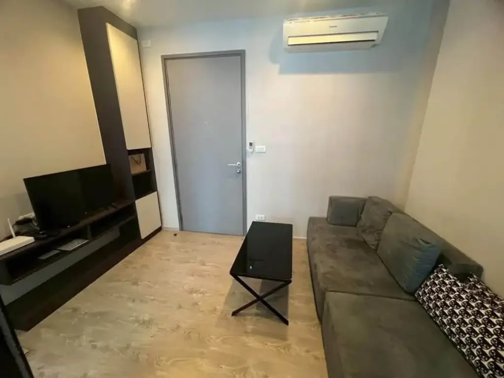 1 Bedroom Condo for Rent at The Base Central Pattaya living room with gray sofa, TV unit, and wall-mounted air conditioner