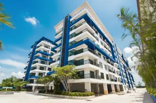 The Blue Residence, a modern multi-story condo building with blue and white facade, balconies, and tropical landscaping.
