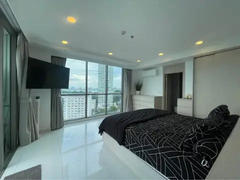 1 Bedroom Condo for Sale at The Cloud bedroom with wall-mounted TV, city view, and black patterned bedding