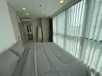 2 Bedroom Condo for Sale at The Cloud bedroom with sheer curtains, brick wall accent, and city view