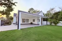 3 Bedroom House for Sale at The Flow Pong - Mabprachan rear exterior with covered patio, tiled terrace and lush green garden at dusk