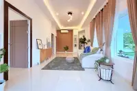 3 Bedroom House for Sale at The Flow Pong - Mabprachan bright living room with tray ceiling, cove lighting, wood panel wall and garden views