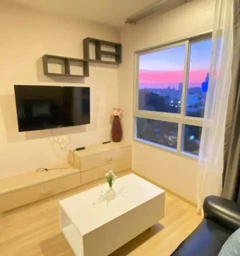2 Bedroom Condo for Rent at The Grass living area with TV and window showing sunset city skyline view