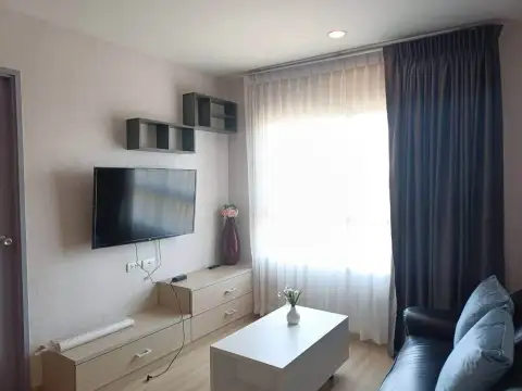 2 Bedroom Condo for Rent at The Grass living room with mounted TV, wooden cabinet, and sofa with pillows
