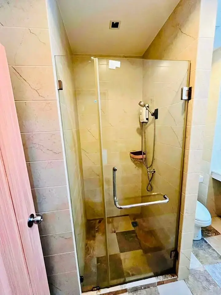 The Green Living Condo bathroom with glass-enclosed shower, marble tile walls, and handheld showerhead