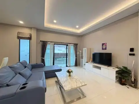 3 Bedroom House for Rent at The Lake Huay Yai living room with gray sofa, TV console, and balcony access