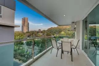 The Lofts Pratumnak spacious balcony with outdoor dining set and scenic views of the city and green hills.