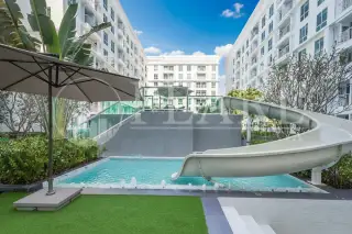 The Orient Resort & Spa outdoor swimming pool area with a water slide and surrounding lush greenery.