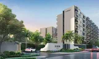 The Origin Pattaya, modern condo buildings with red, grey, and white facades, a central driveway, and landscaping.