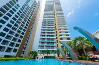 The Peak Towers rooftop infinity pool with a clear blue sky, modern metallic sculptures, and panoramic ocean views.