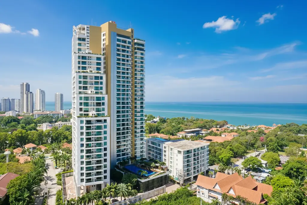 The Peak Towers high-rise condominium building with multiple balconies, surrounded by green trees, overlooking the ocean.