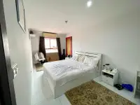 1 Bedroom Condo for Sale at The Place Pratumnak bright bedroom with white bed and patterned area rug