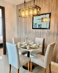 2 Bedroom Condo for Sale at The Point Pratumnak dining area with wooden accent wall and modern chandelier